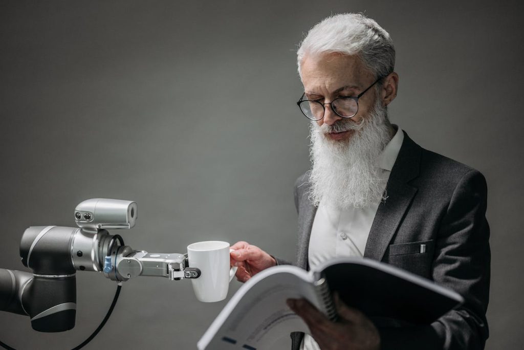 Man reading while accepting a cup of coffee from a robot